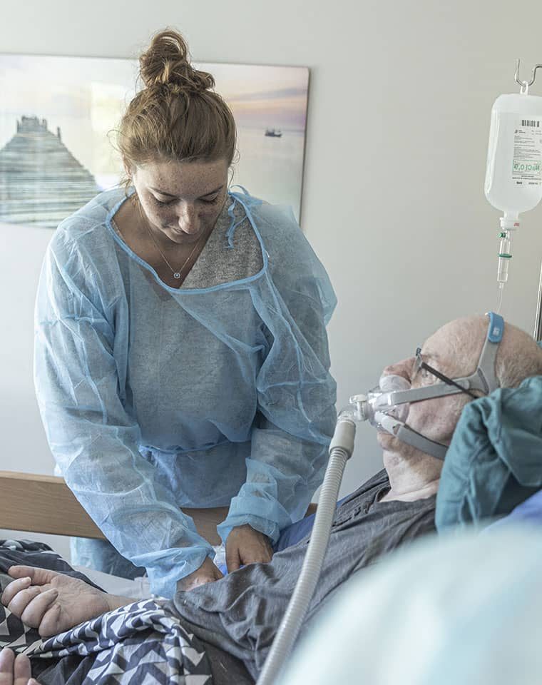 Soignante s'occupe d'un patient à domicile sous respirateur